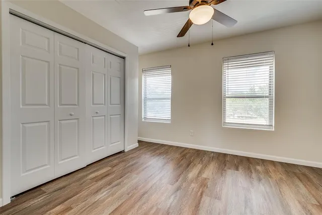 a view of an empty room with window and wooden floor