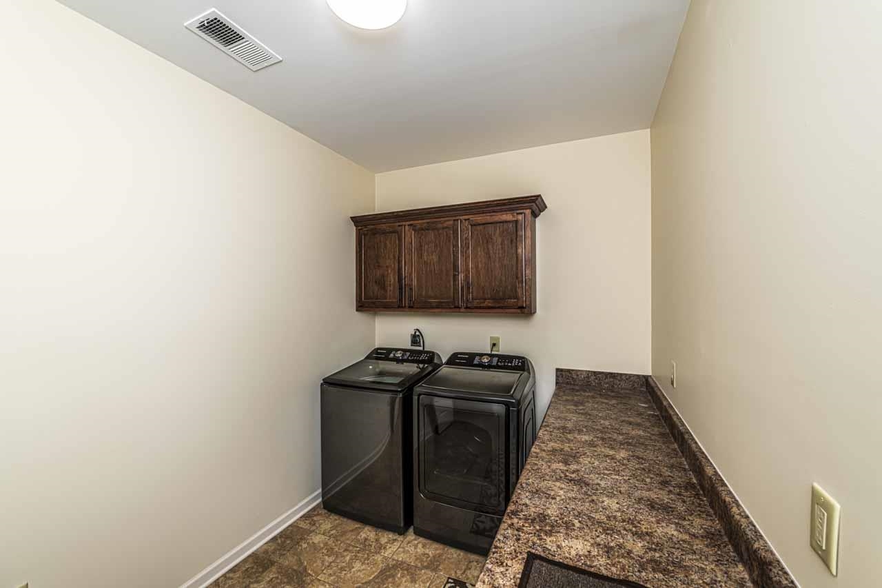 185 Belmont Road Mason, TN 38049 - Photo 17 of 38 Utility room with patterned flooring, dark wood-finish cabinetry, and a spacious countertop