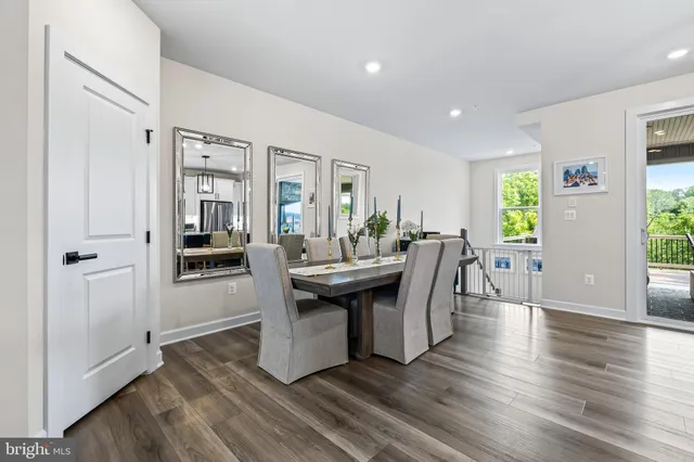 a room with stainless steel appliances kitchen island granite countertop a table chairs and a living room view