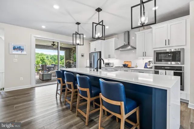a kitchen with stainless steel appliances a sink a stove a table and chairs