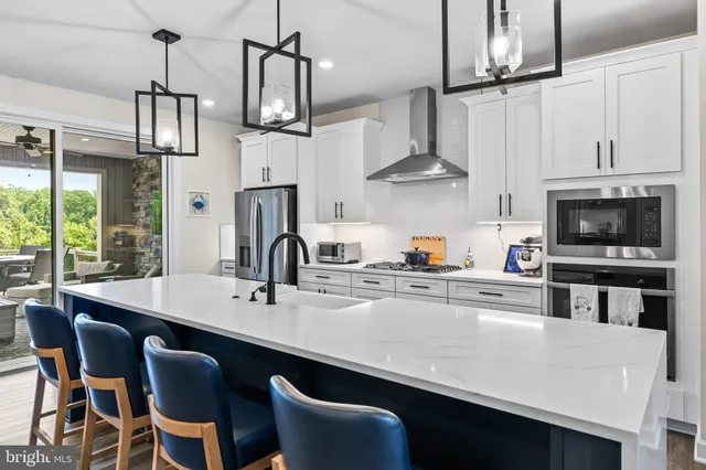 a kitchen with stainless steel appliances kitchen island granite countertop a stove a sink a oven a dining table and chairs with wooden floor