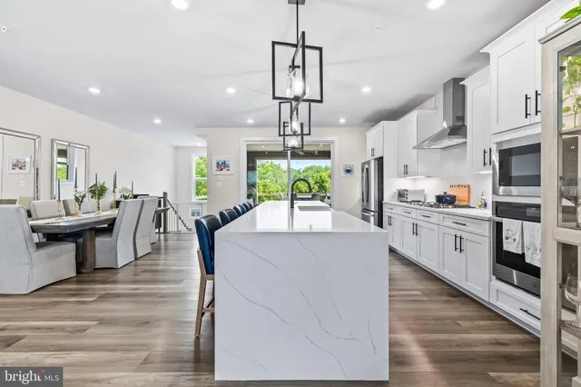 a kitchen with stainless steel appliances a sink and wooden floor