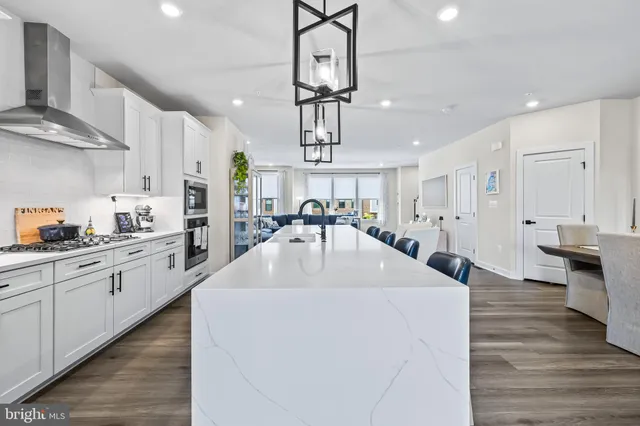 a kitchen with stainless steel appliances a dining table chairs and stove
