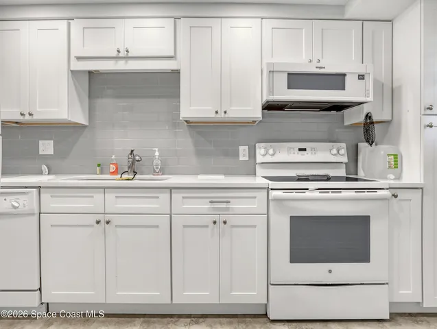 a kitchen with white cabinets and white appliances