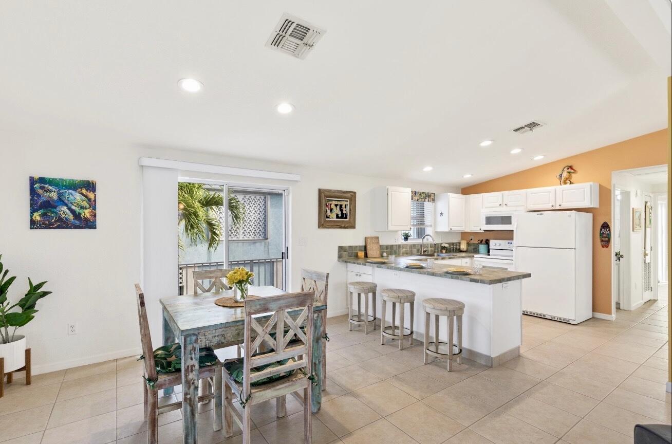 157 Mars Lane Key West, FL 33040 - Photo 14 of 41 a kitchen with a dining table chairs refrigerator and cabinets