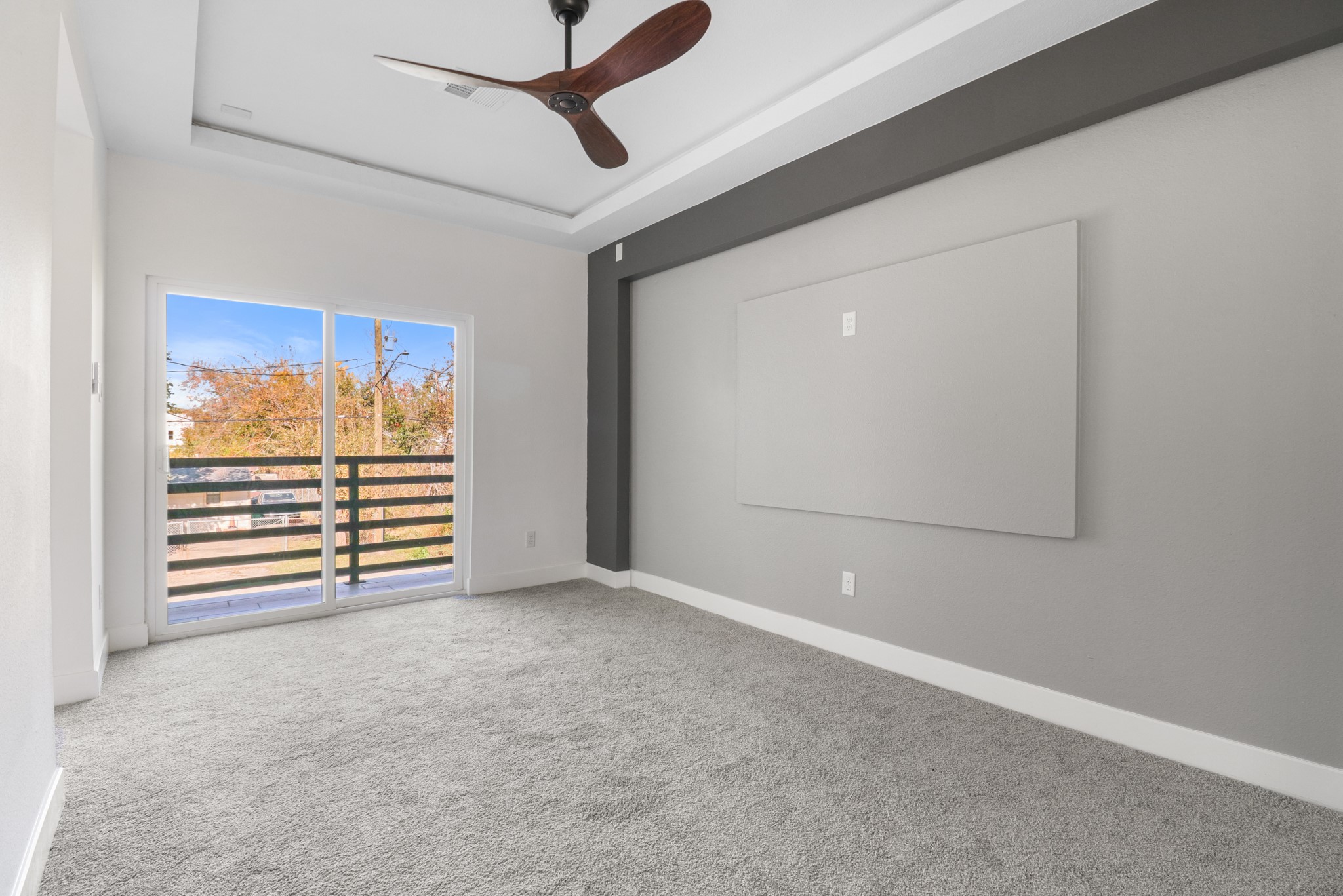 8046 Chateau Street Houston, TX 77028 - Photo 11 of 22 This room features soft gray carpeting, a modern ceiling fan, and a large window with sliding glass doors leading to an outdoor view. The walls are a mix of light and dark gray tones, creating a sleek, contemporary feel.