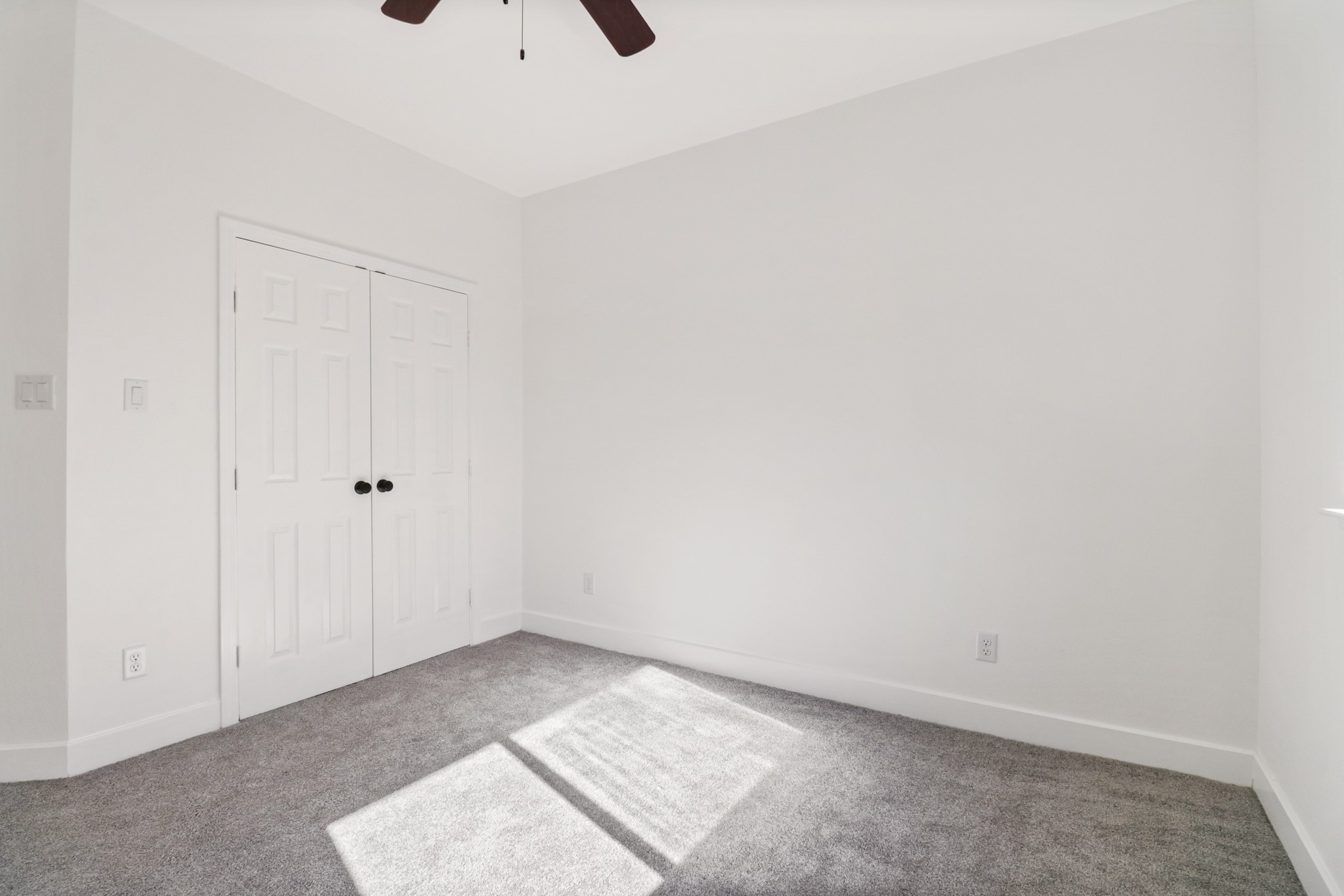 8046 Chateau Street Houston, TX 77028 - Photo 18 of 22 Bright, minimalist bedroom with neutral walls, carpeted floor, and a ceiling fan. Features a double-door closet, perfect for storage. Natural light enhances the space, creating a cozy atmosphere.