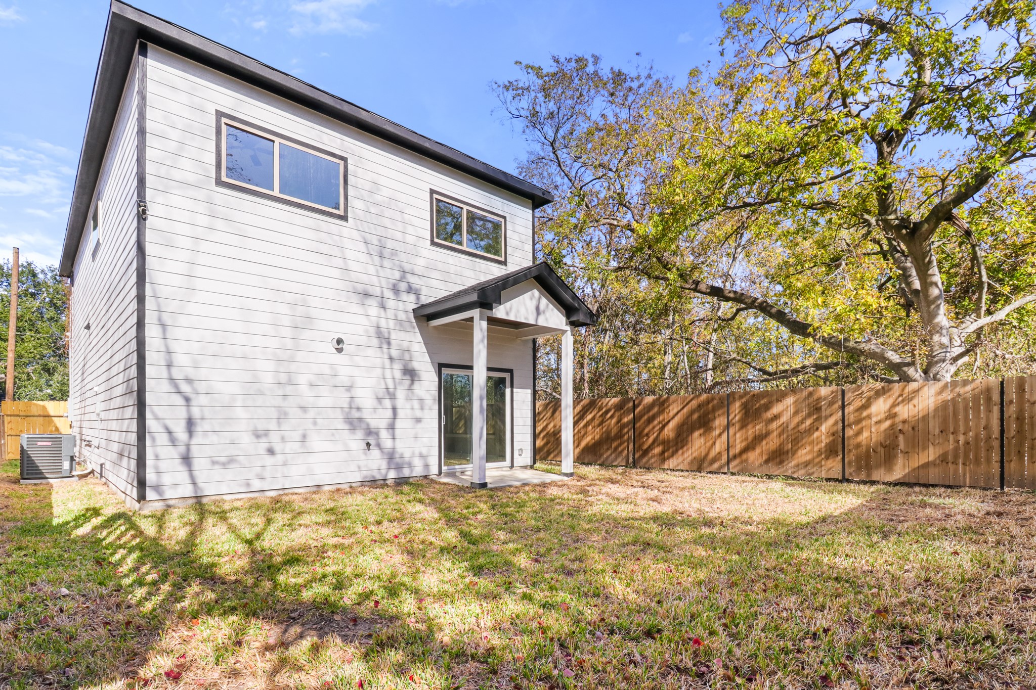 8046 Chateau Street Houston, TX 77028 - Photo 22 of 22 Modern two-story home with gray siding, large windows, and a spacious fenced backyard. Perfect for outdoor activities and privacy.