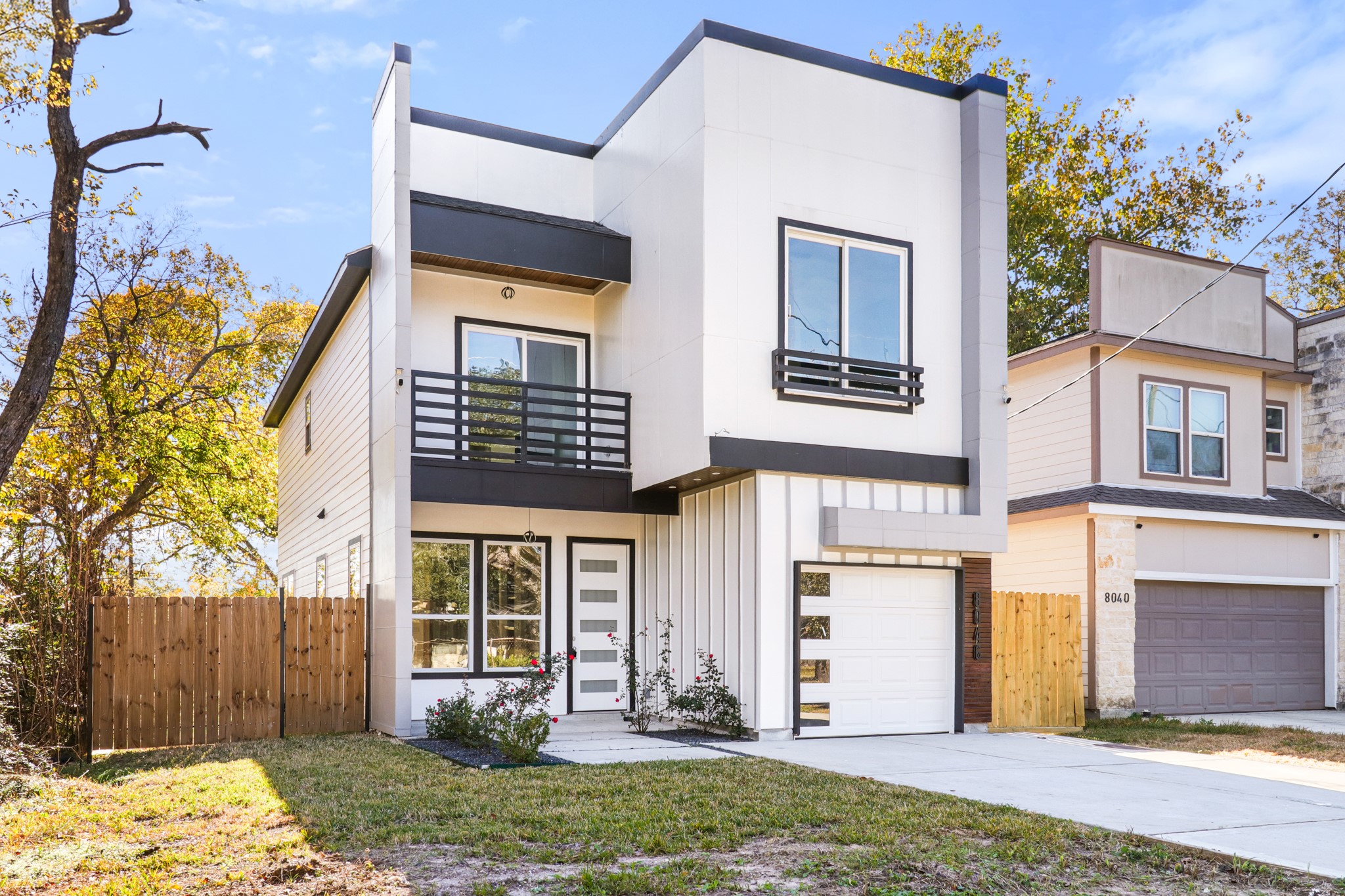 8046 Chateau Street Houston, TX 77028 - Photo 3 of 22 This modern two-story home features a sleek facade with clean lines, large windows, and a balcony. It's complemented by a single-car garage and a fenced yard, providing privacy and a touch of nature in the front.