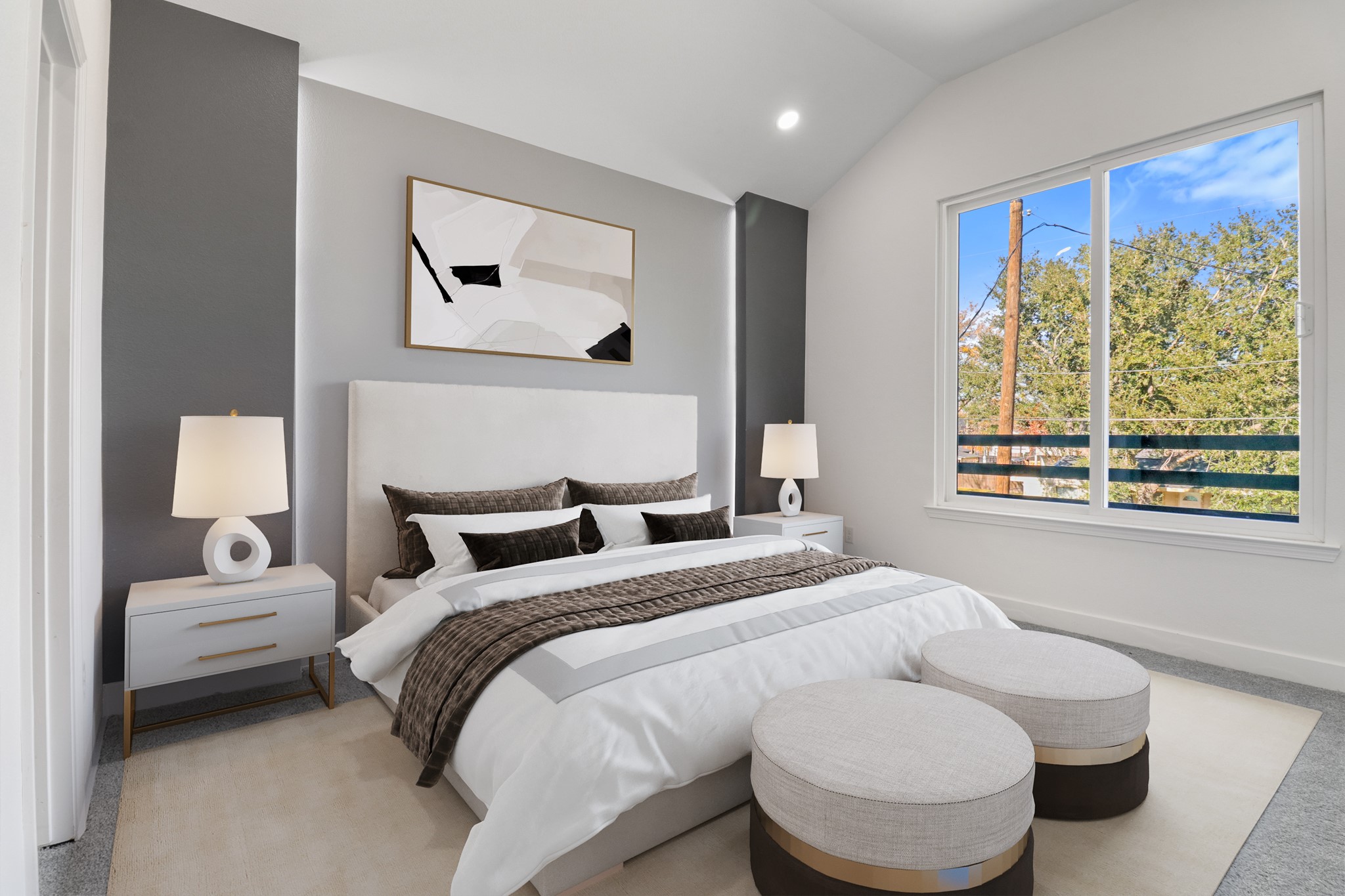 8046 Chateau Street Houston, TX 77028 - Photo 8 of 22 This bedroom features a modern design with a neutral color palette, a large window offering natural light, and stylish furnishings including a plush bed, bedside tables with lamps, and decorative artwork. The space is inviting and serene, perfect for relaxation.