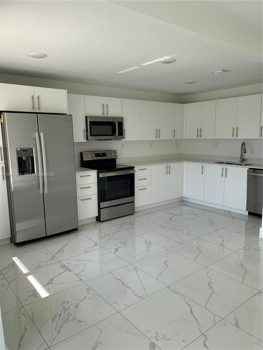 25822 Southwest 144th Court, Unit 25822 Homestead, FL 33032 - Photo 4 of 19 a kitchen with stainless steel appliances granite countertop a sink and a stove