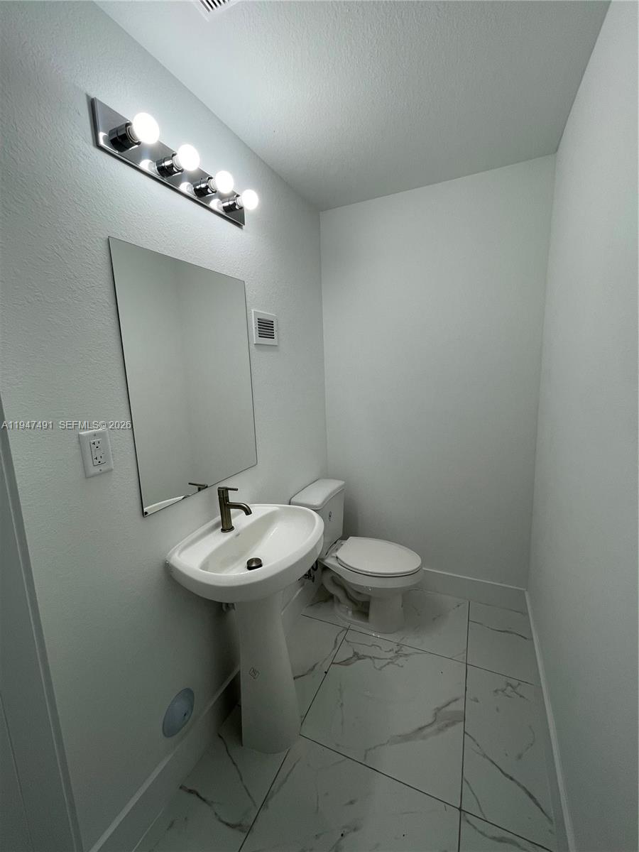 25822 Southwest 144th Court, Unit 25822 Homestead, FL 33032 - Photo 7 of 19 a bathroom with a sink a toilet and a mirror