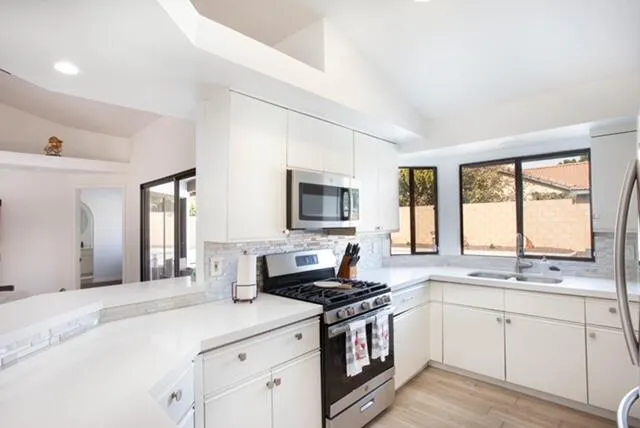 a kitchen with stainless steel appliances granite countertop a sink stove cabinets and wooden floor