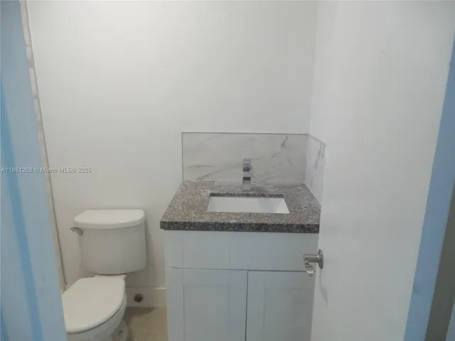 a bathroom with a granite countertop toilet and sink
