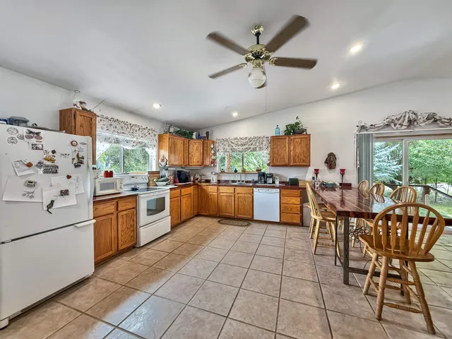 a kitchen with a dining table chairs and white appliances