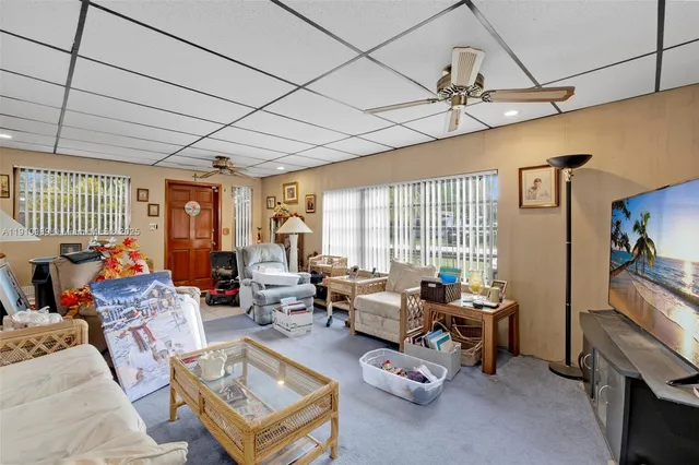 a living room with furniture a flat screen tv and a large window