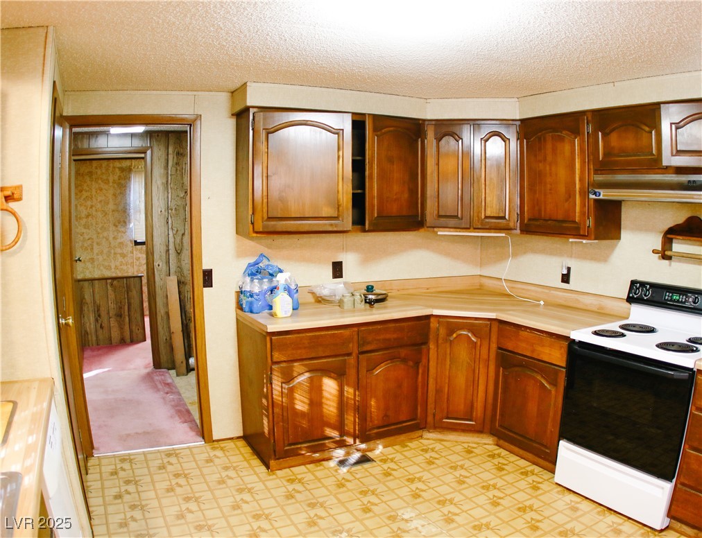 31 South 4th Street Panaca, NV 89042 - Photo 20 of 36 Kitchen featuring range with electric cooktop, light countertops, a textured ceiling, under cabinet range hood, and light floors