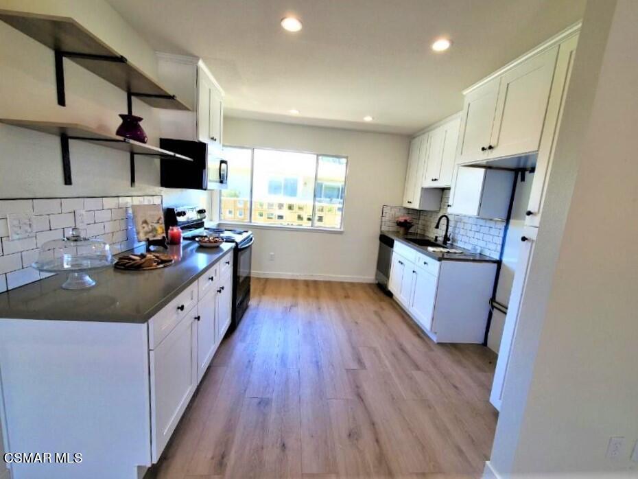 a large kitchen with stainless steel appliances granite countertop a lot of counter space and wooden floors