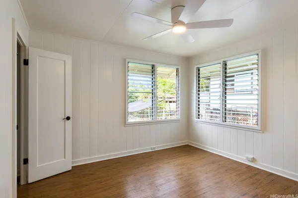a view of an empty room with a window and wooden floor