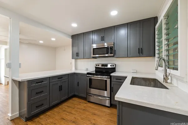 a kitchen with granite countertop stainless steel appliances a stove a sink a microwave and cabinets