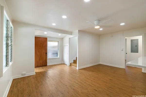 a view of an empty room with wooden floor and a window