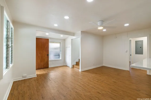 a view of an empty room with wooden floor and a window