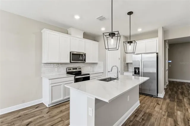 a kitchen with stainless steel appliances granite countertop a refrigerator a microwave a sink and white cabinets