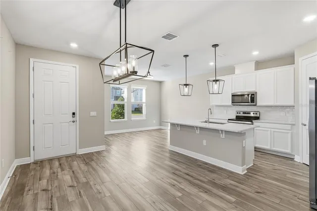 a kitchen with granite countertop white cabinets stainless steel appliances and a counter space