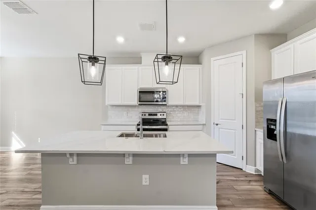 a kitchen with stainless steel appliances kitchen island a refrigerator and a view of living room