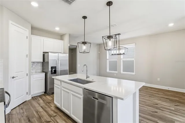 a large kitchen with a wooden floor and stainless steel appliances