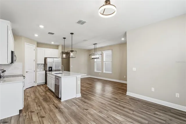 a kitchen with stainless steel appliances a sink a stove a refrigerator cabinets and wooden floor