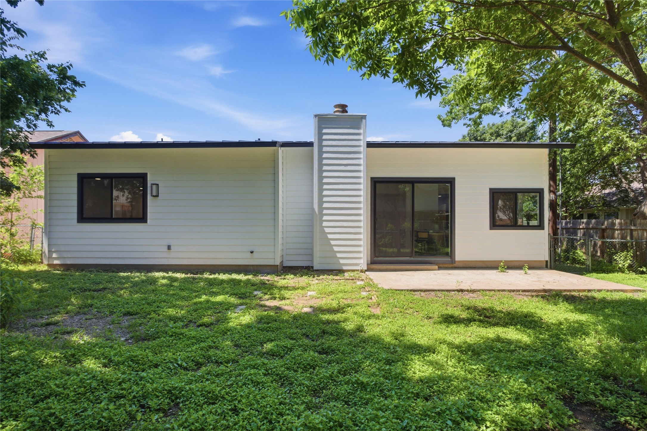 2110 Magazine Street Austin, TX 78727 - Photo 28 of 31 Back exterior featuring white horizontal siding, black window frames, a concrete patio, and a sliding glass door