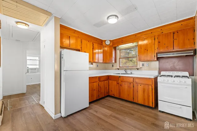 a kitchen with stainless steel appliances granite countertop a refrigerator a sink dishwasher a stove and white countertops with wooden floor