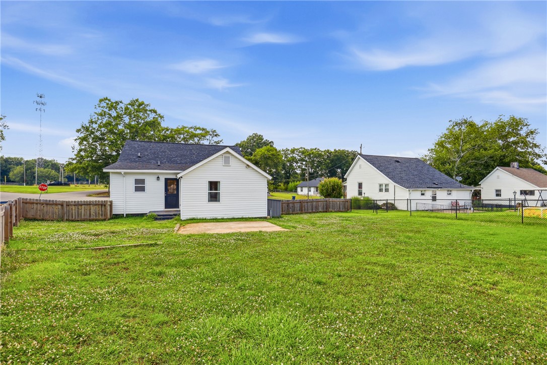 1 Brock Street Pelzer, SC 29669 - Photo 23 of 25 A spacious yard offers ample outdoor living potential, framed by a charming white home.