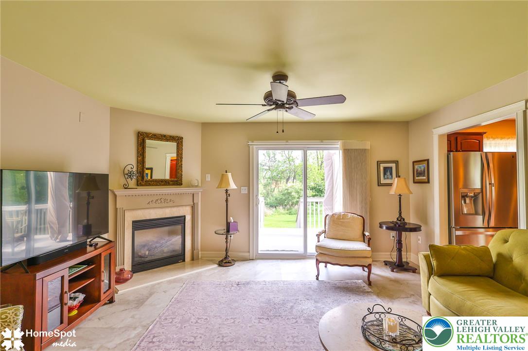 4191 Walter Road Bethlehem, PA 18020 - Photo 13 of 23 A cozy living room features a fireplace, a ceiling fan, and sliding glass doors that open to the outdoors.