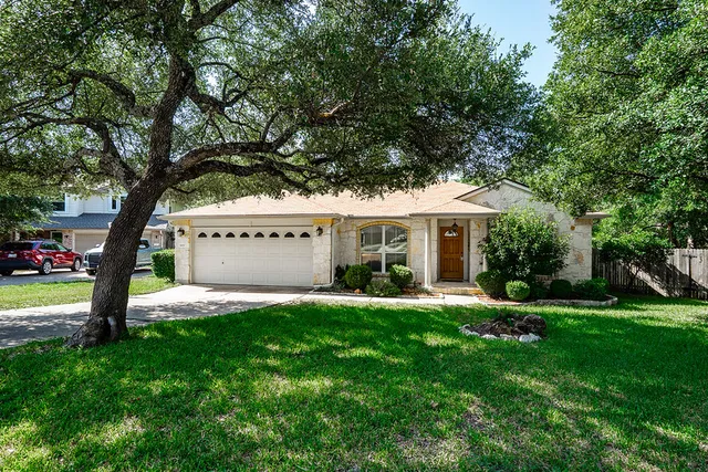 a front view of a house with a yard and a tree