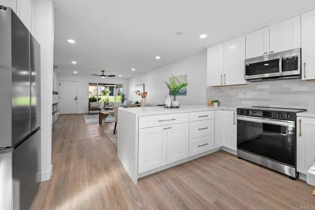 a kitchen with stainless steel appliances a white stove top oven a sink dishwasher and a fireplace with wooden floor