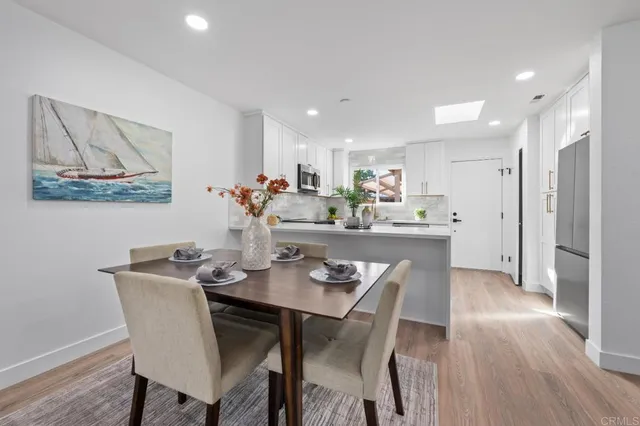 a kitchen with stainless steel appliances granite countertop a dining table and chairs with wooden floor