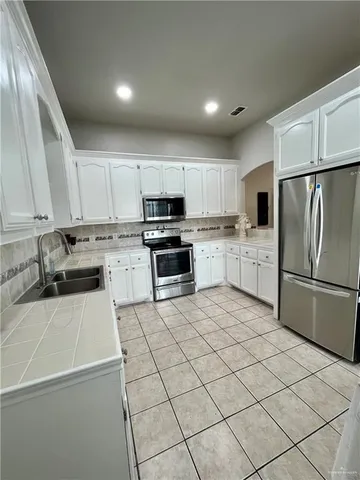 a kitchen with granite countertop a refrigerator sink and white cabinets