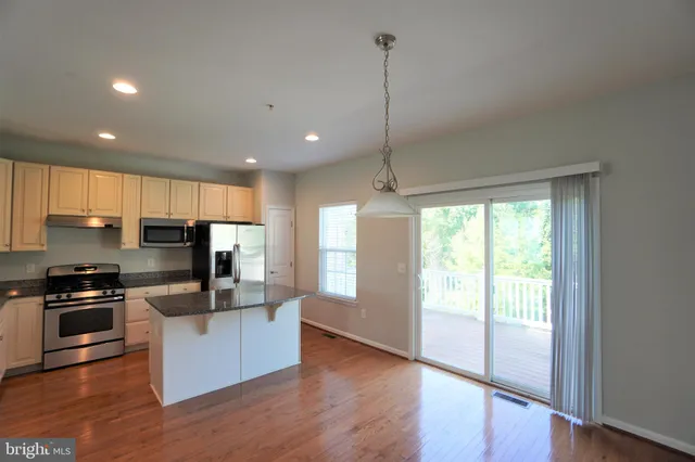 a kitchen with stainless steel appliances granite countertop a refrigerator a sink a stove and a wooden floors