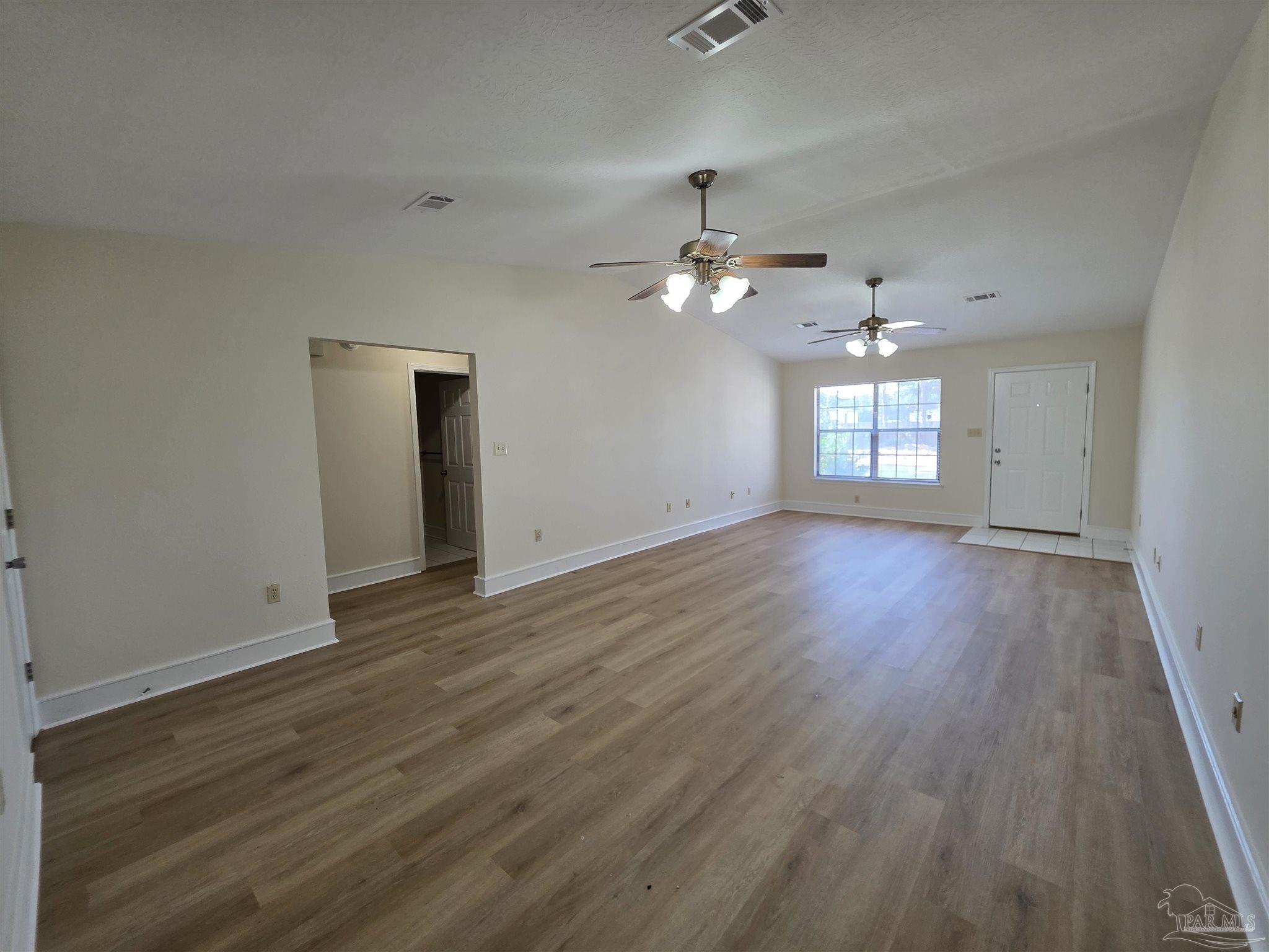 916 Rentz Avenue, Unit A Pensacola, FL 32507 - Photo 5 of 22 an empty room with wooden floor chandelier fan and windows