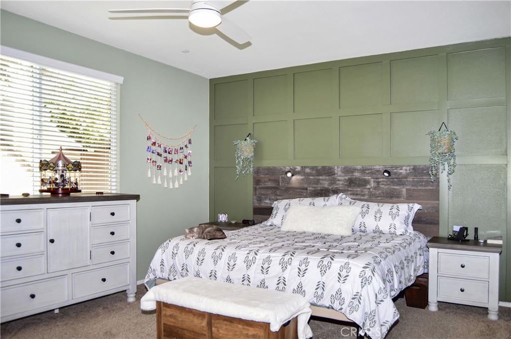 166 Fox Lane Calimesa, CA 92320 - Photo 32 of 76 Inviting Main Bedroom Suite with Custom Headboard with Reading Lights, Matching TV Surround with Shelving, Wood Panel Accents, a Ceiling Fan, and Cozy Carpeting