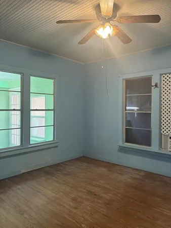 en empty room with window and chandelier fan