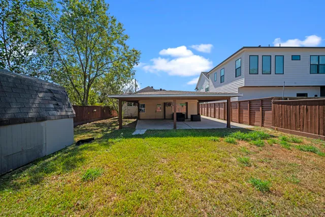 a view of a house with a yard porch and wooden fence