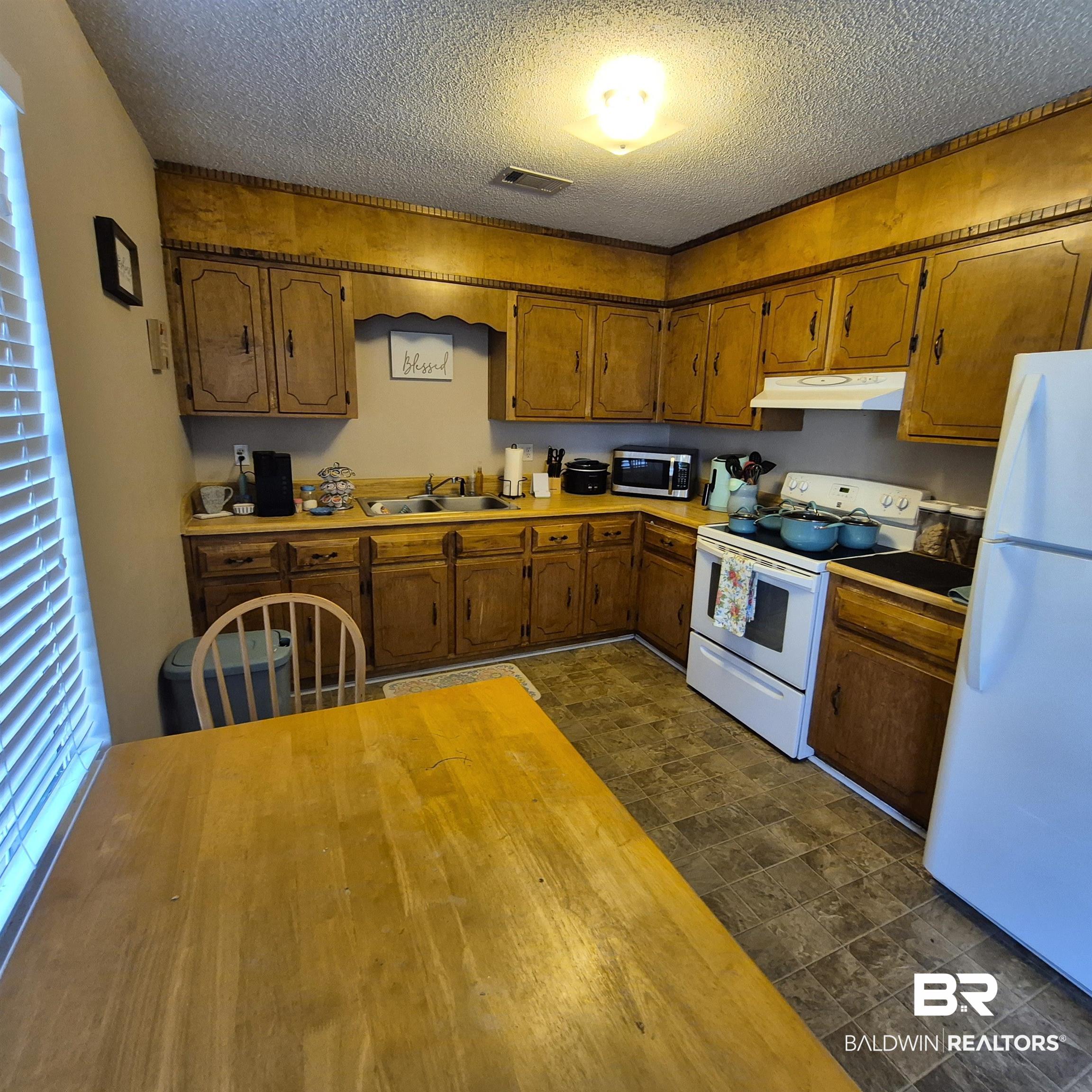 721 Perryman Street Evergreen, AL 36401 - Photo 11 of 26 Kitchen with white appliances, wood finish cabinetry, and a textured ceiling
