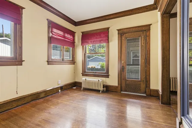 a view of an empty room with window and wooden floor