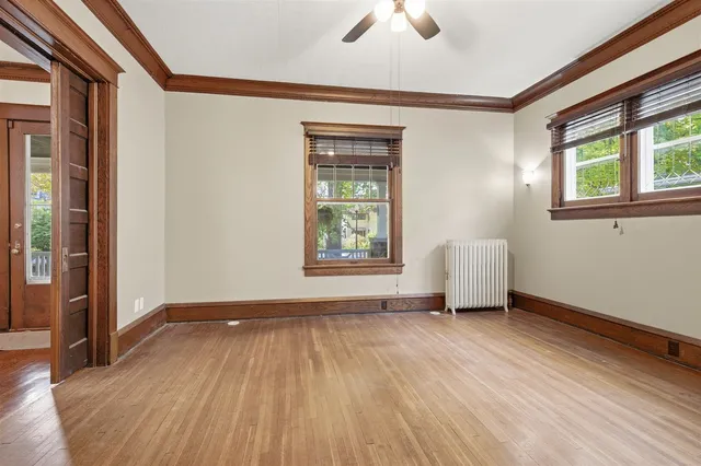 a view of an empty room with a window and wooden floor