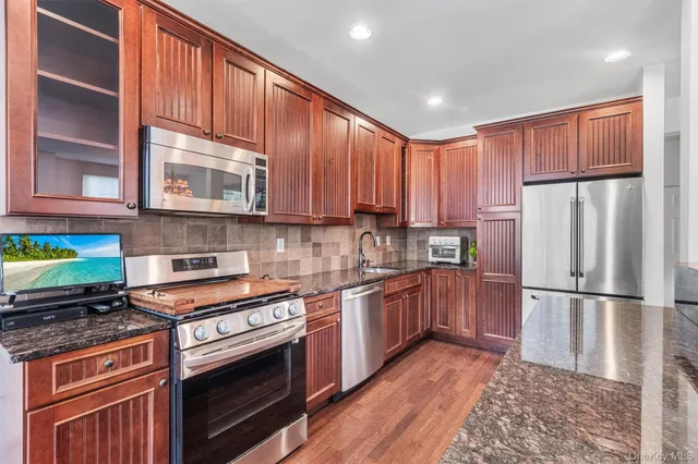 a kitchen with stainless steel appliances granite countertop wooden cabinets a stove a sink and a refrigerator