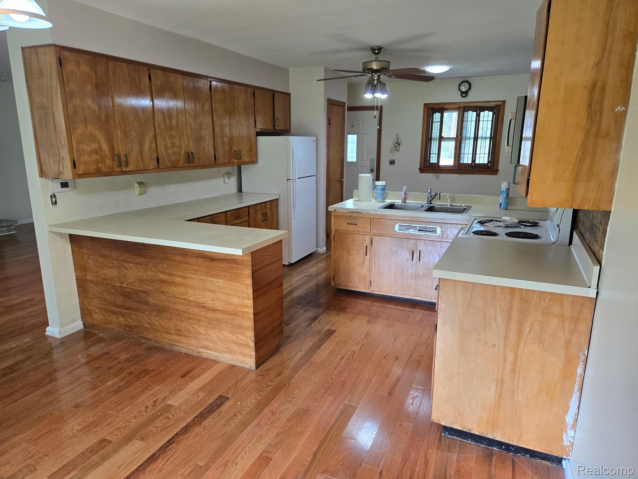 3176 East Fisher Road Bay City, MI 48706 - Photo 3 of 25 Kitchen with a peninsula, brown cabinetry, light countertops, white appliances, and light wood finished floors