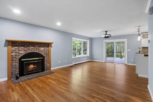 an empty room with wooden floor fireplace cabinet and windows